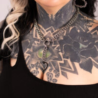 Silberne Choker-Kette mit herzförmigem Anhänger auf tätowierter Haut