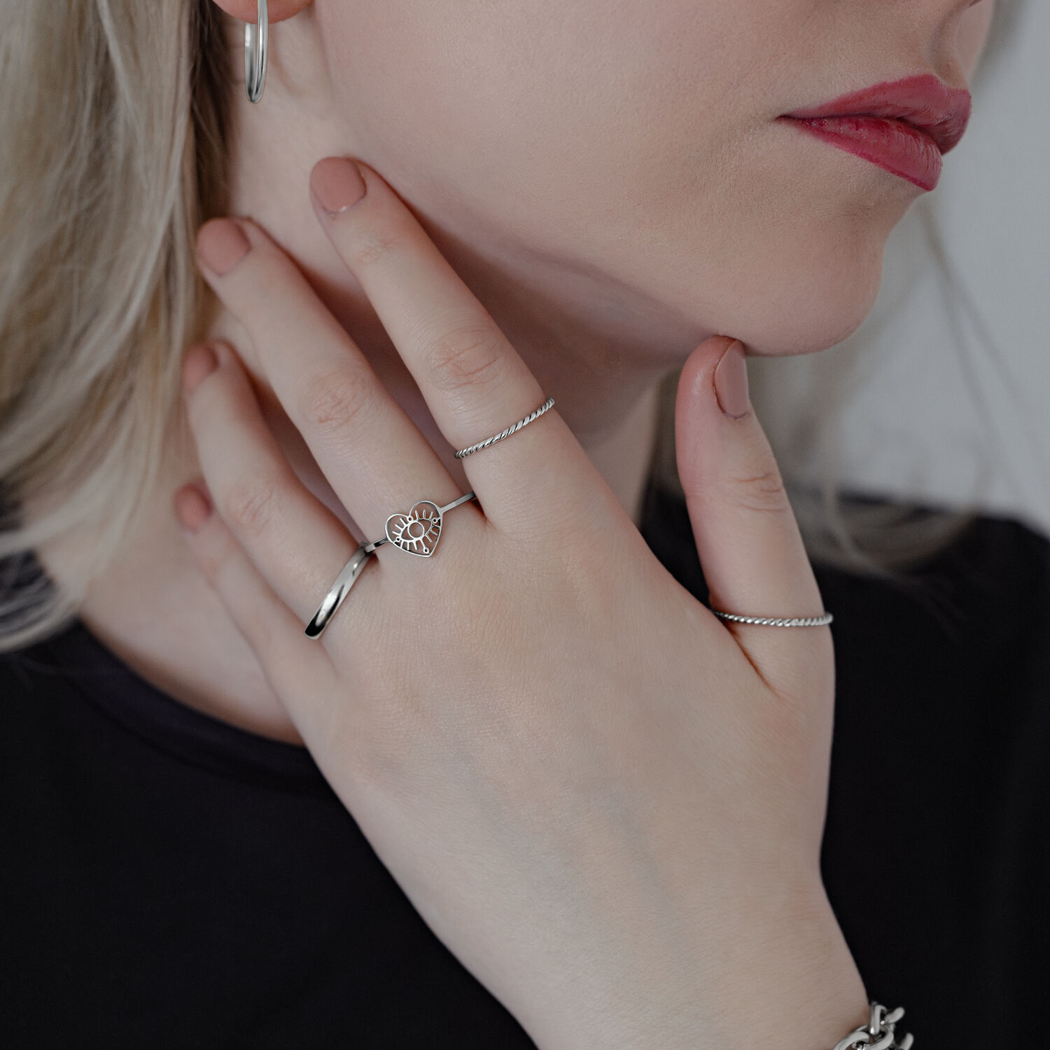 Eleganter Eye Ring aus Chirurgenstahl Frau trägt mehrere Ringe, darunter ein Eye Ring in Silber auf hellem Hintergrund