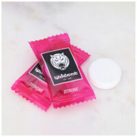 Wildcat Zitronen-Dextrosetabletten 1000 Stk. Zwei pinke Wildcat Zitronen-Dextrosetabletten auf Marmorhintergrund