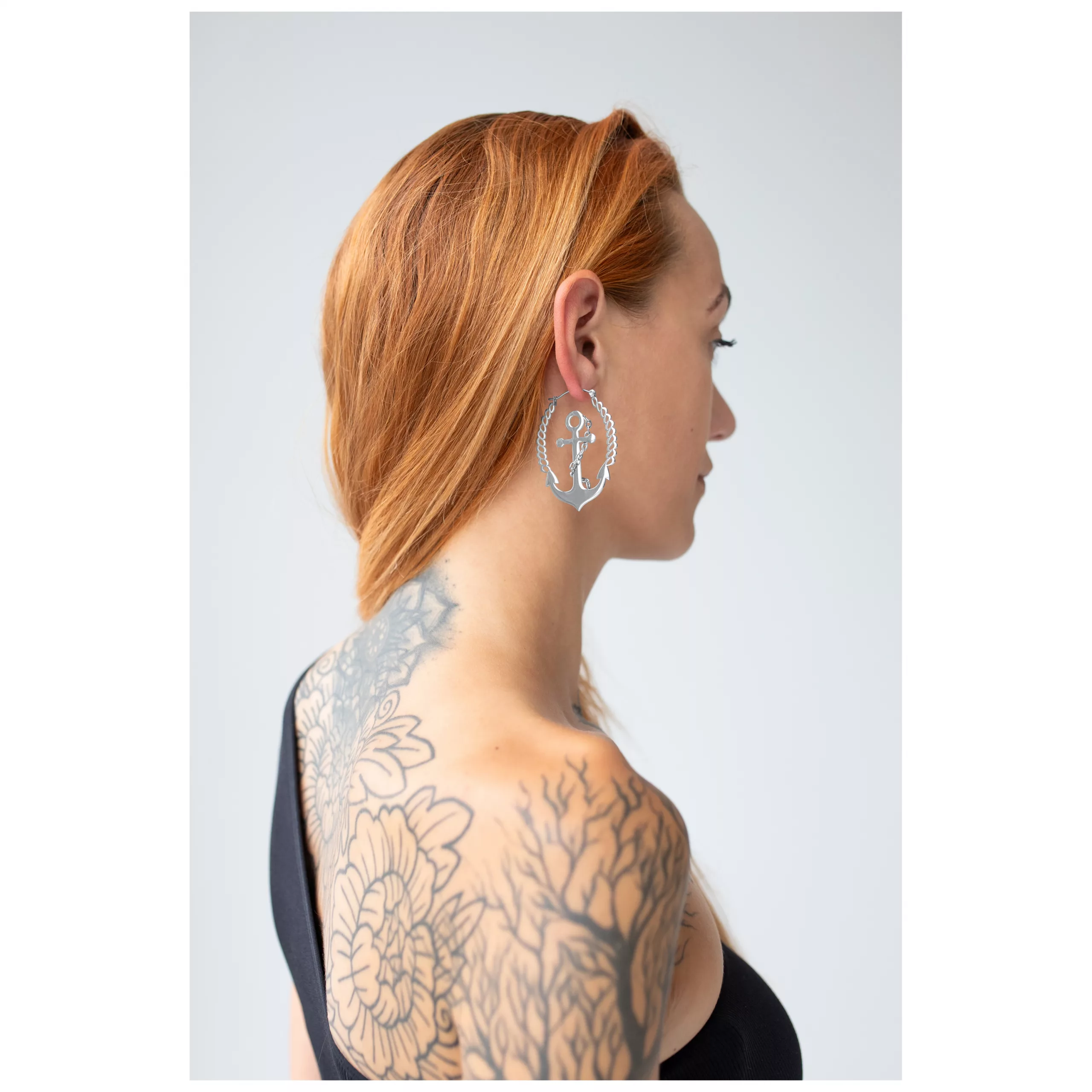 Stylishe Chain Anchor Hoops Ohrringe Frau mit roten Haaren trägt silberne Chain Anchor Hoops vor hellem Hintergrund