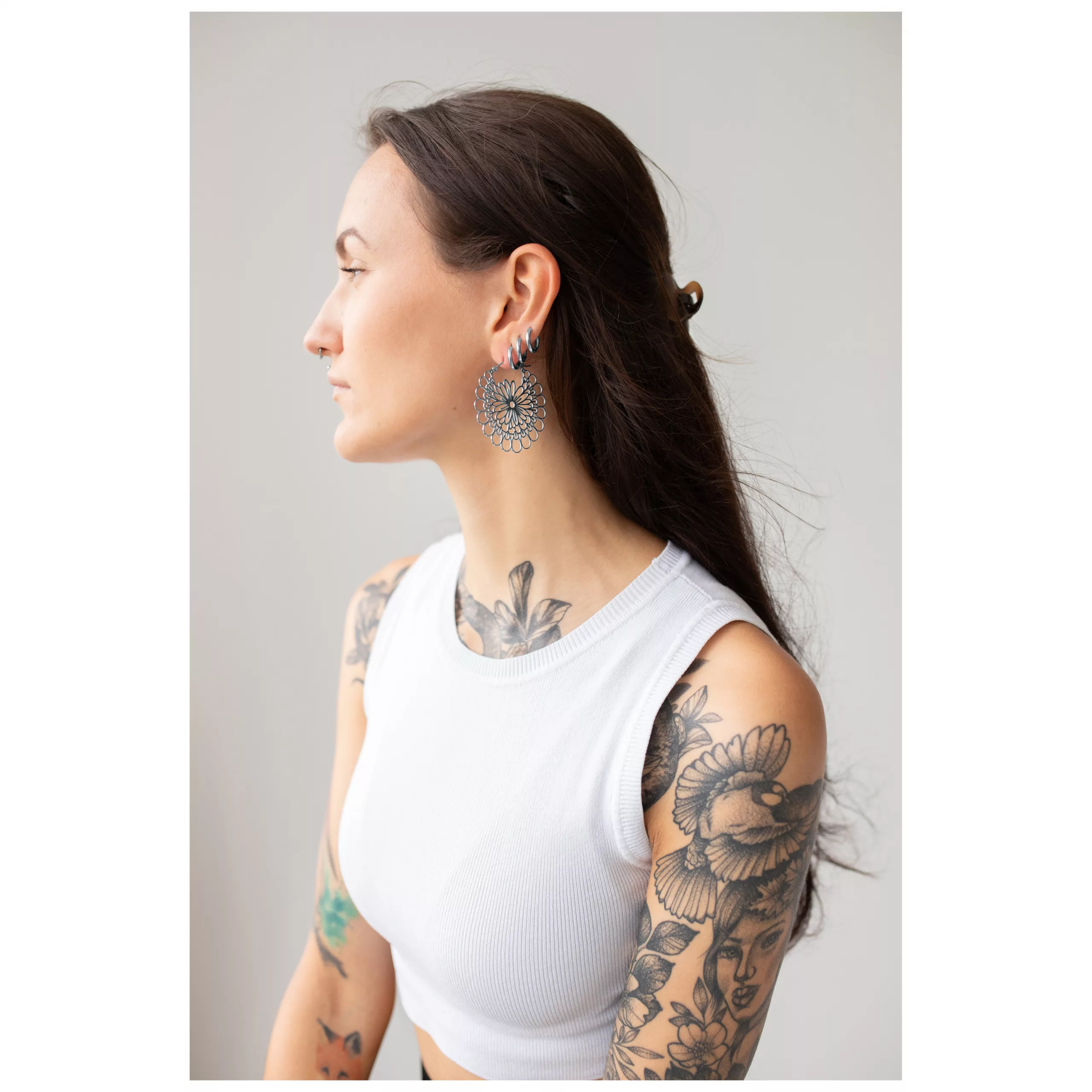 Daisy Hoops Ohrringe in Schwarz und Silber Frau mit Daisy Hoops Ohrringen in Schwarz und Silber vor grauem Hintergrund