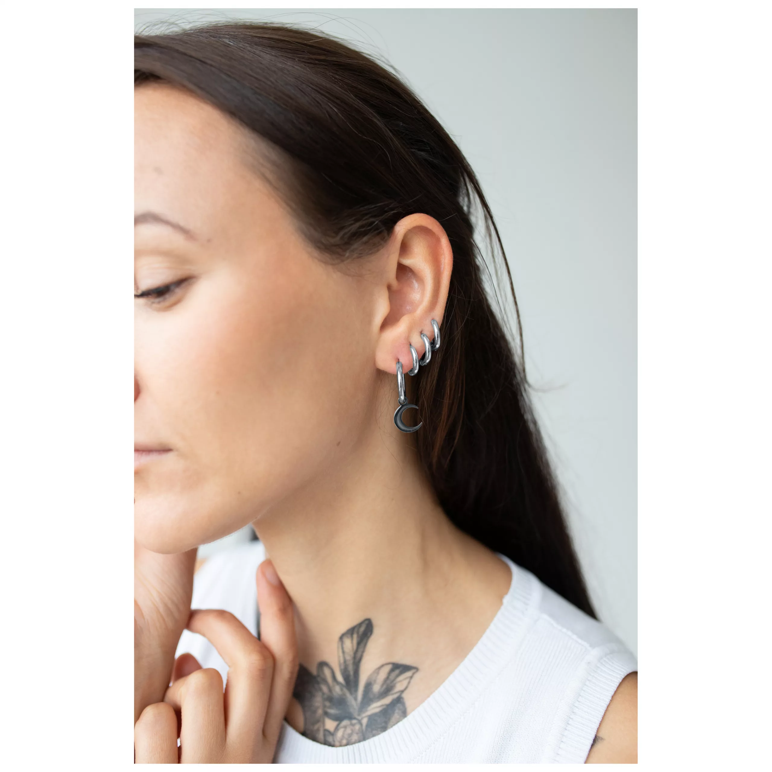 Elegante Little Moonchild Hoops in Schwarz Frau mit schwarzen Little Moonchild Hoops, seitlich im Ohr getragen