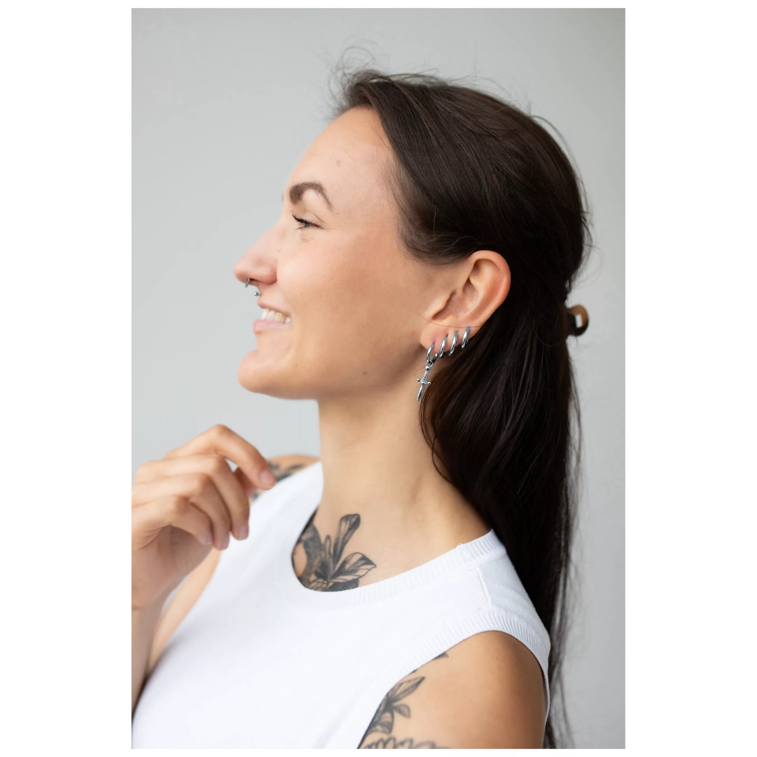 Elegante Little Sword Hoops Ohrringe Frau mit langen, dunklen Haaren trägt silberne Little Sword Hoops Ohrringe auf hellem Hintergrund