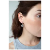 Silberne Little Luminous Eye Hoops Ohrringe Frau trägt silberne Ohrringe mit Augenmotiv, seitliche Ansicht