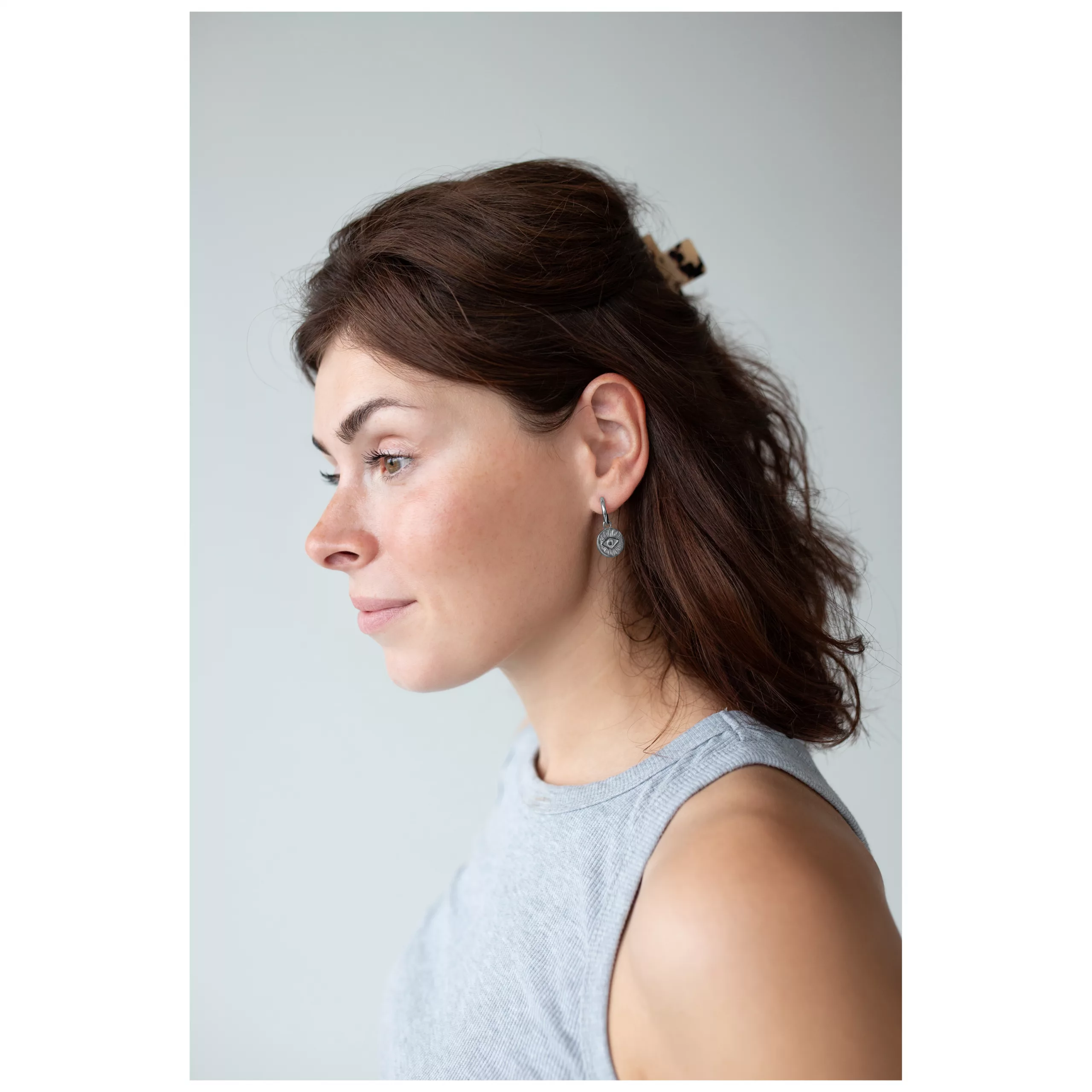 Little Luminous Eye Hoops am Ohr getragen Frau mit braunem Haar trägt Little Luminous Eye Hoops, seitliche Ansicht