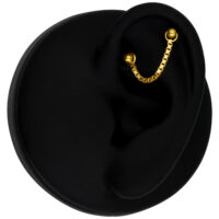 14K Gold Piercingkette an schwarzem Ohr Goldene Piercingkette aus 585er Gold an einem schwarzen Ohr auf schwarzem Hintergrund