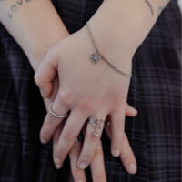 Elegantes Silberarmband mit Herzanhänger Silbernes Armband mit Herzanhänger an Handgelenk, getragen von einer Person.