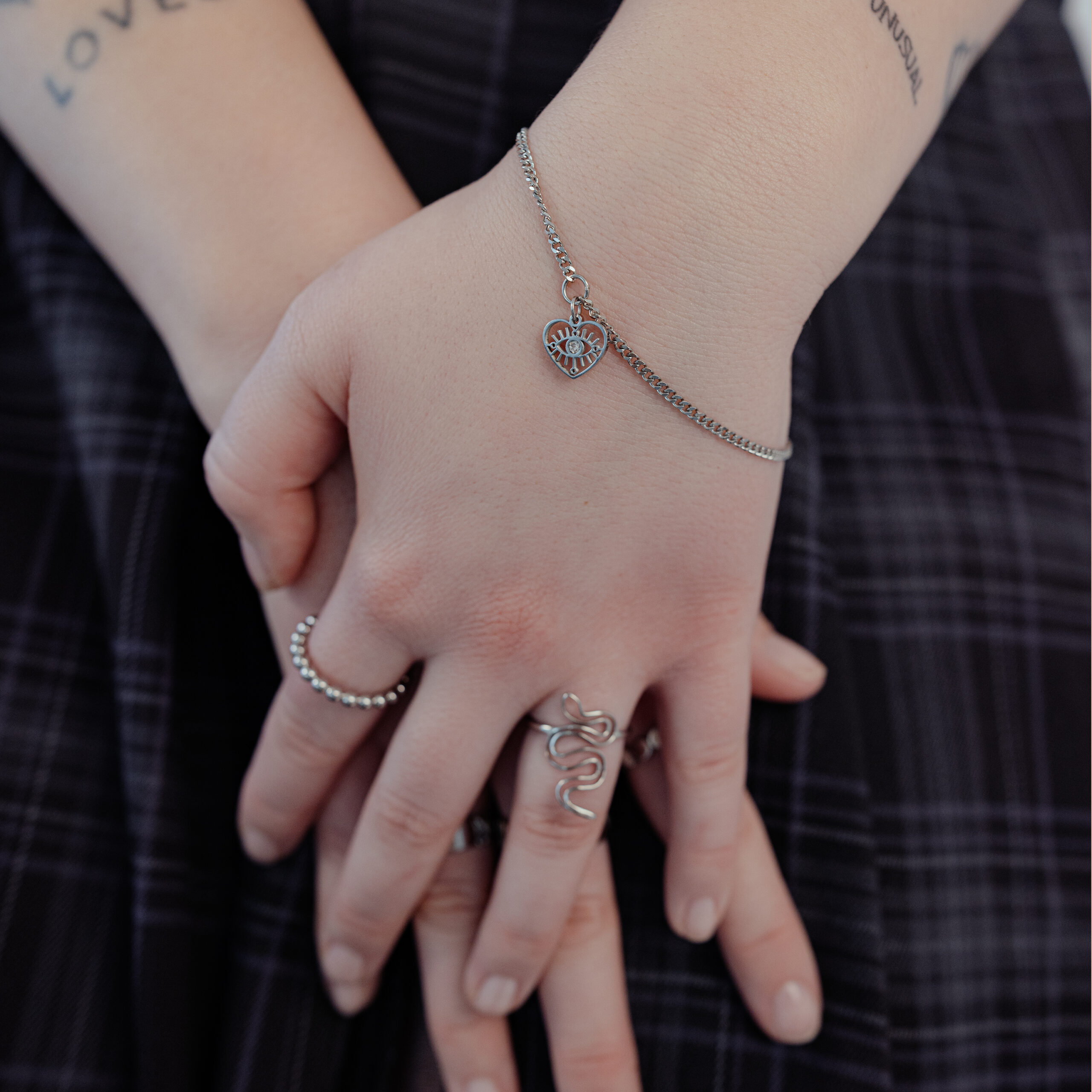 Elegantes Silberarmband mit Herzanhänger Silbernes Armband mit Herzanhänger an Handgelenk, getragen von einer Person.