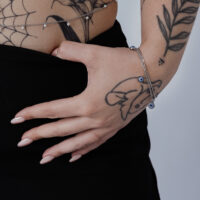 Silbernes Armband mit Nazar-Anhänger am Handgelenk, tätowierte Hand