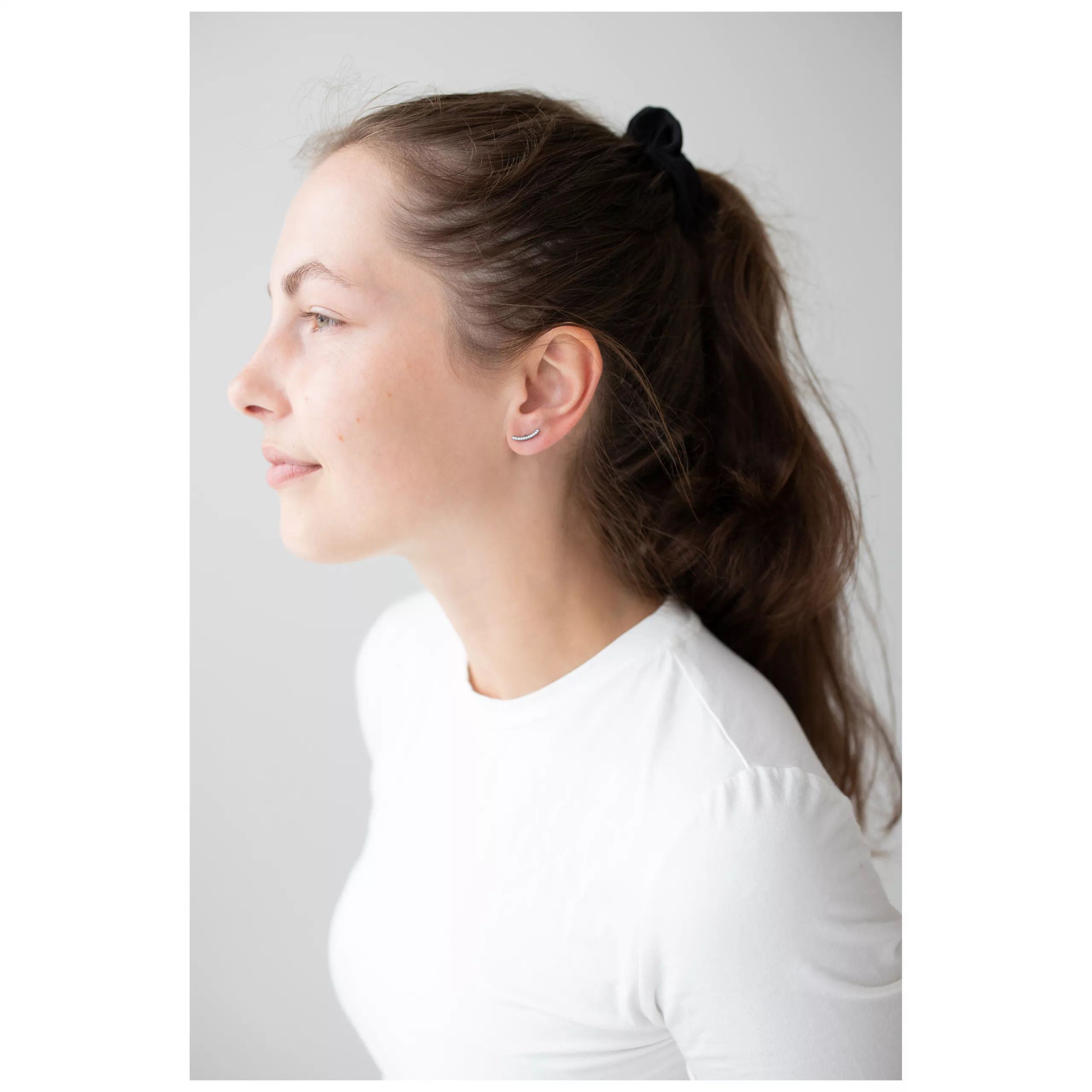 Elegante Crystal Arch Ohrstecker für Damen Frau mit Crystal Arch Ohrsteckern und weißem Oberteil