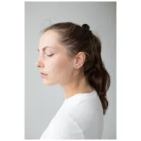 Elegante Schwert-Ohrstecker in Silber Frau mit langen Haaren trägt elegante Schwert-Ohrstecker in Silber vor grauem Hintergrund