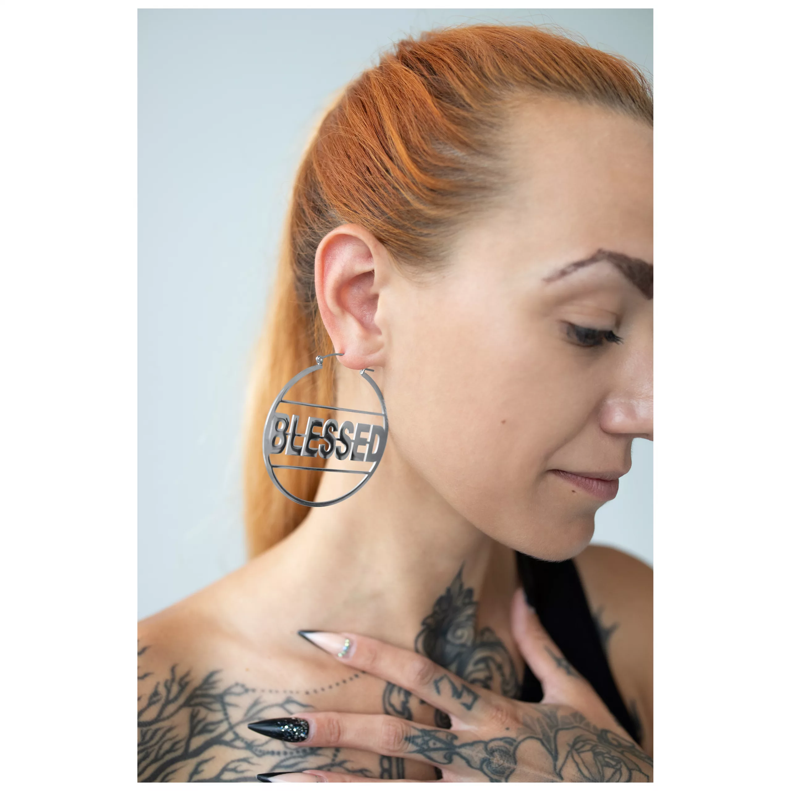 Silberne Blessed Hoops Ohrringe im Ohr getragen Silberne Blessed Hoops Ohrringe aus Edelstahl, am Ohr einer Frau, vor neutralem Hintergrund