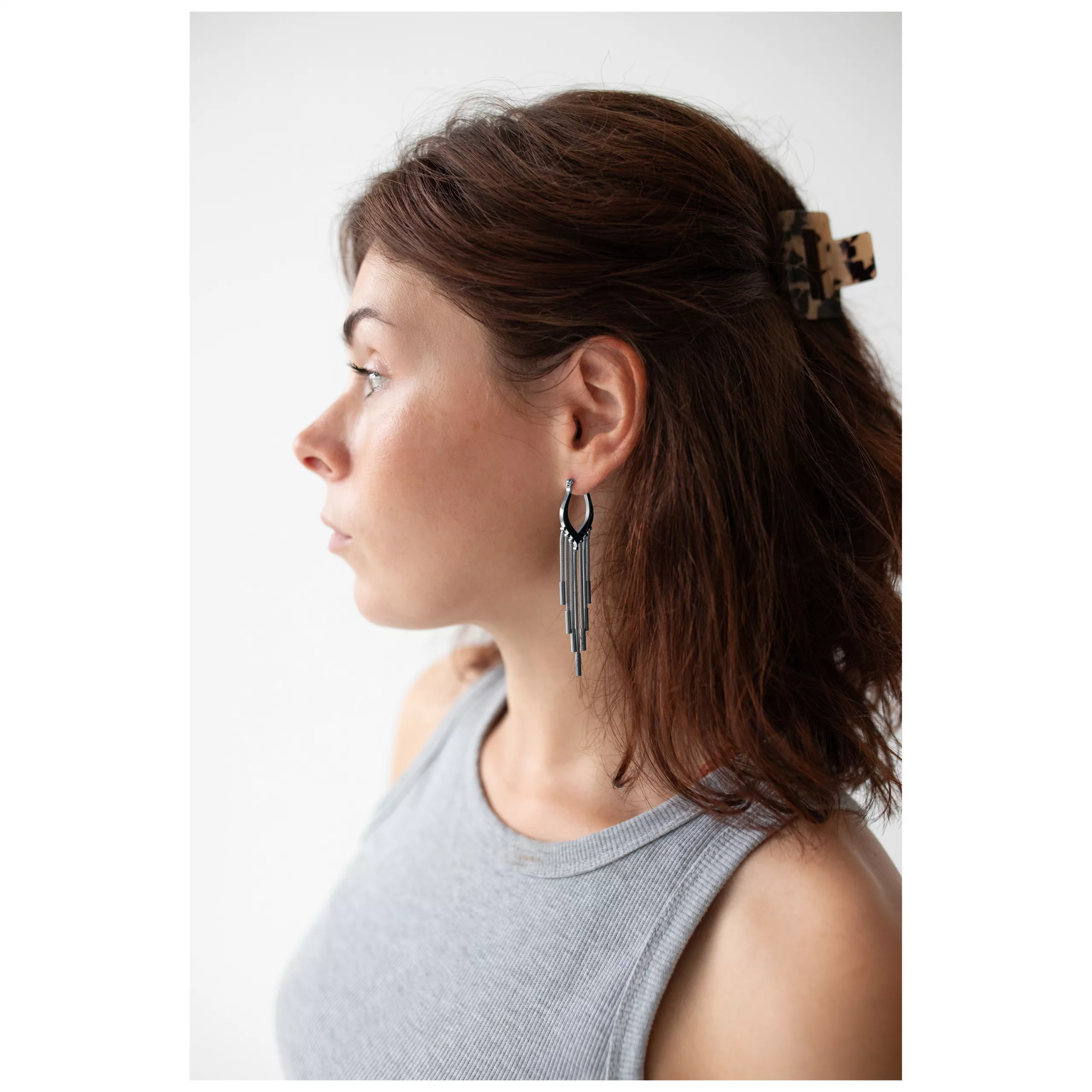 Schwarze Snakechain Hoops am Ohr getragen Frau mit braunem Haar trägt schwarze Snakechain Hoops Ohrringe vor weißem Hintergrund
