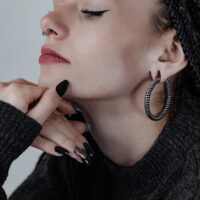 Twisted Rope Ohrgewichte aus Chirurgenstahl Frau mit großen, schwarzen Twisted Rope Ohrgewichten und dunklem Pullover