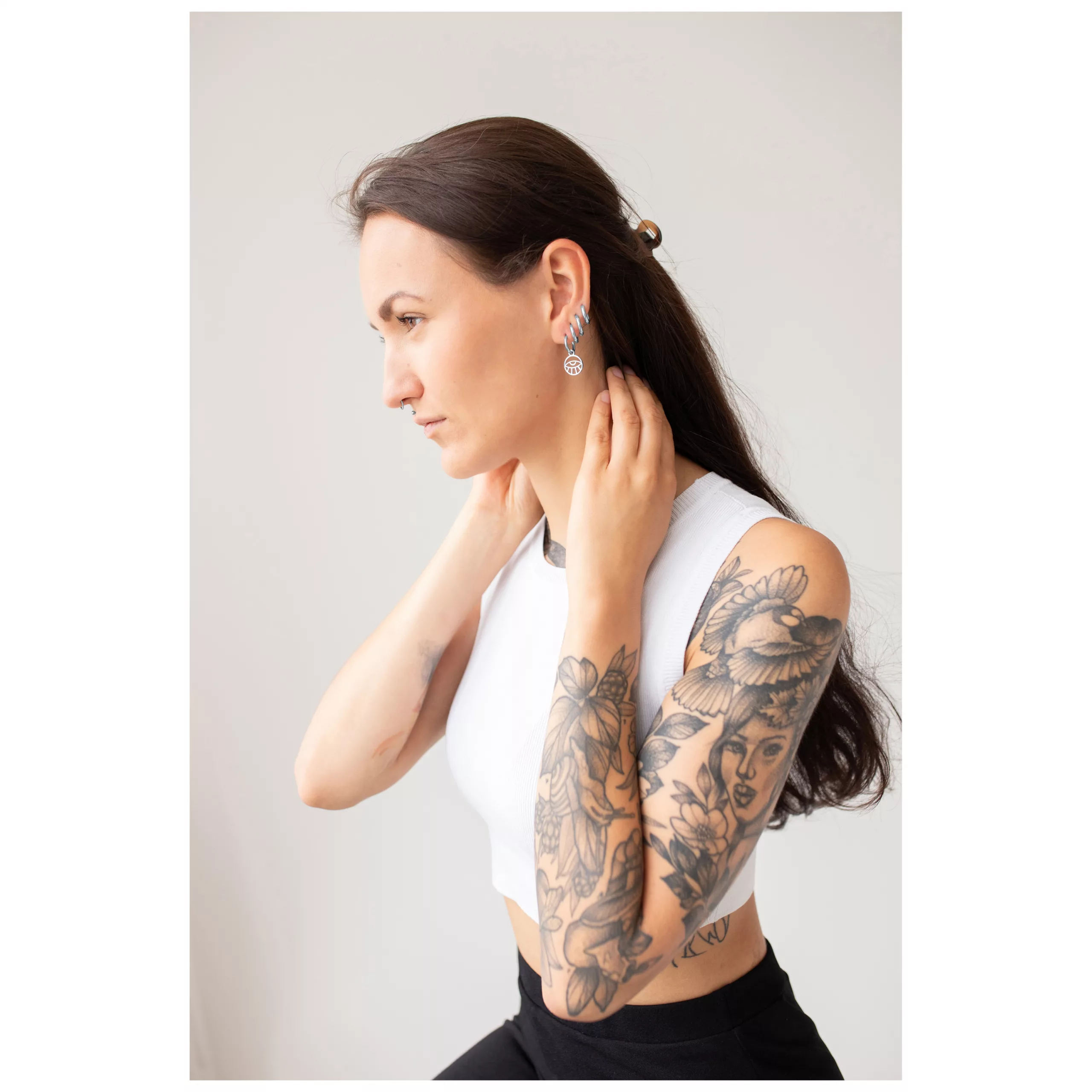 Little Eye Hoops getragen von Frau Frau mit langen Haaren und Tattoos trägt Little Eye Hoops Ohrringe