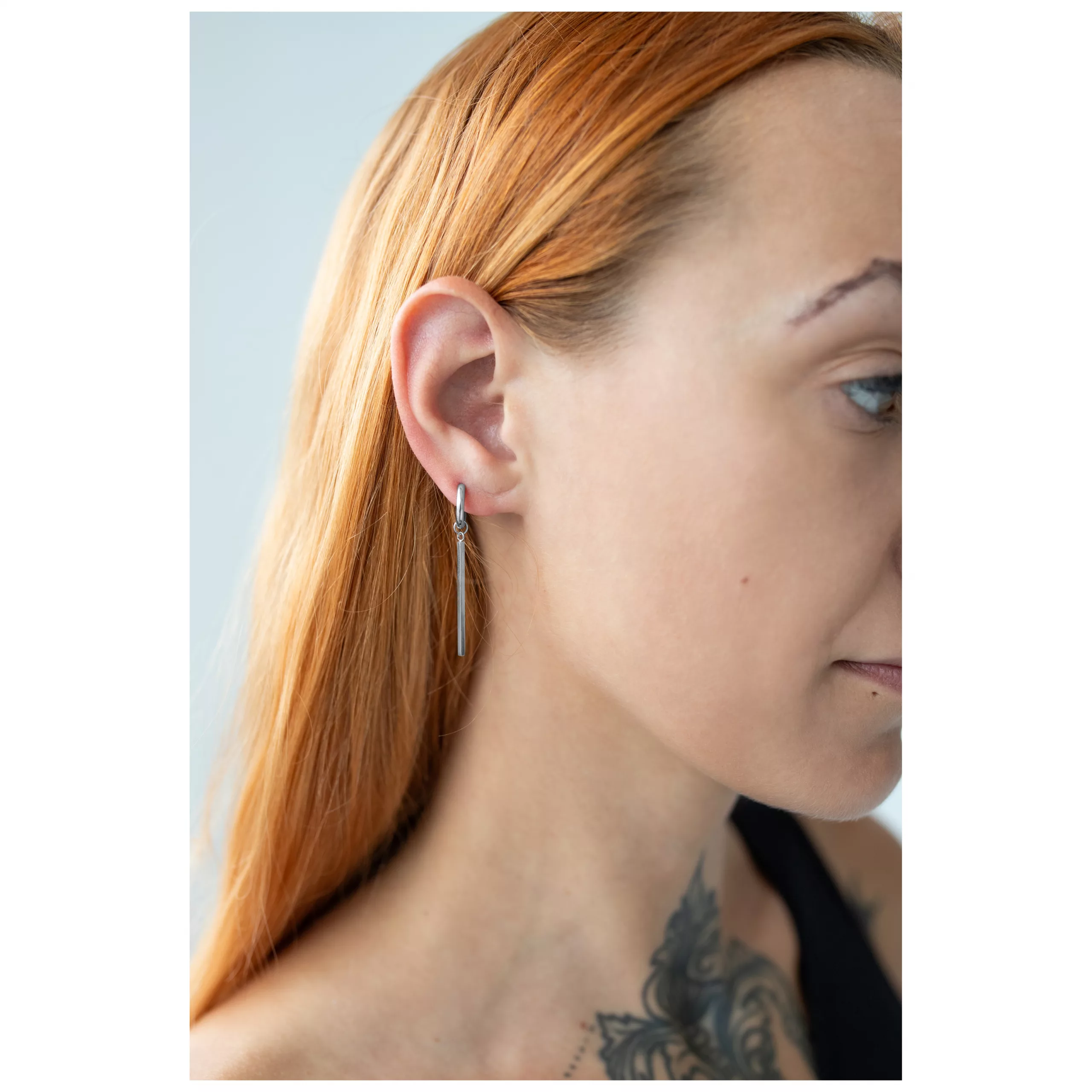 Elegante Bar Hoops Ohrringe aus Chirurgenstahl Frau mit langen, glatten Haaren trägt glänzende Bar Hoops Ohrringe aus silbernem Chirurgenstahl