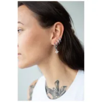 Silberne Little Polar Star Hoops im Ohr Frau trägt silberne Ohrringe mit Sternanhänger auf weißem Hintergrund