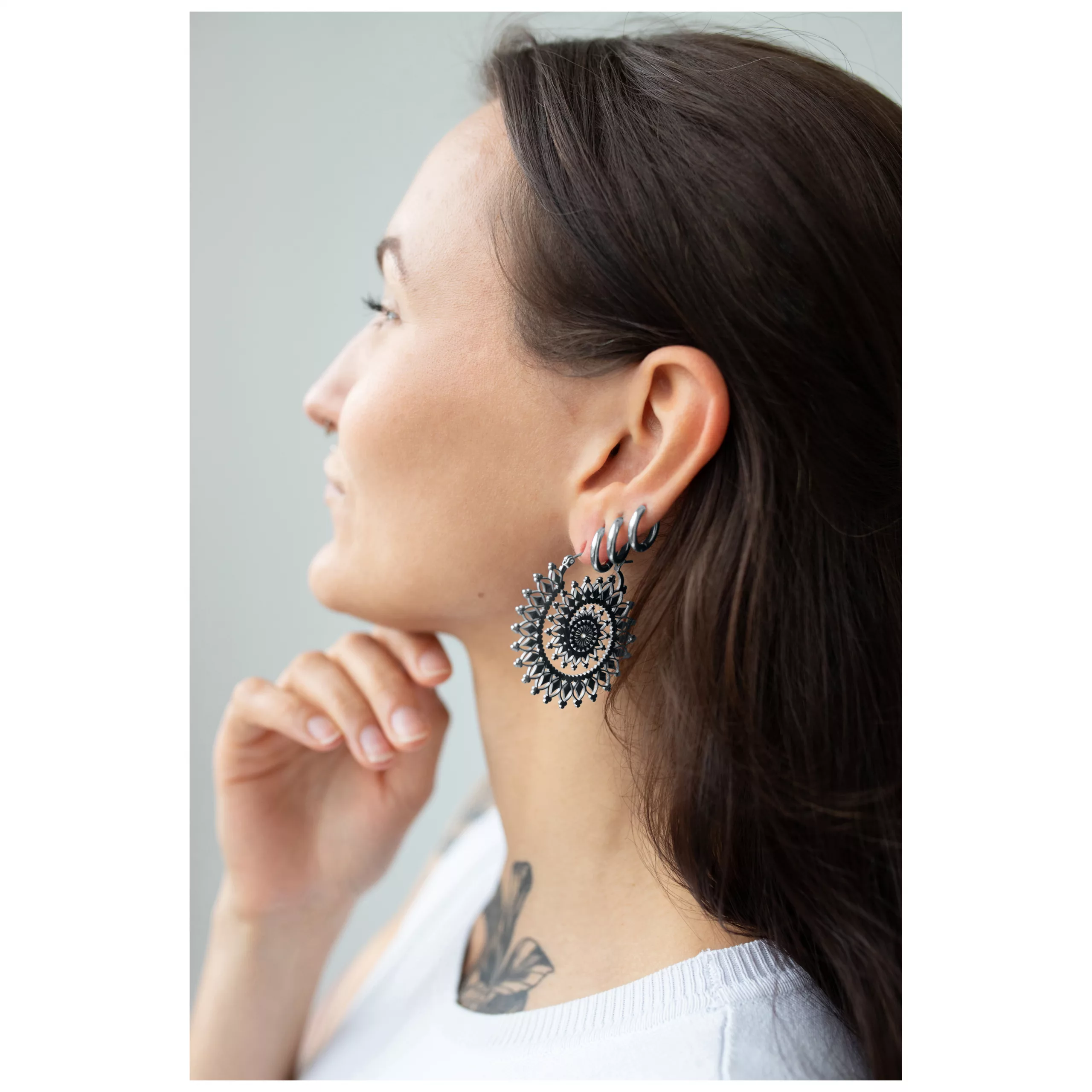 Floral Nautilus Hoops in Silber-Gold Frau mit silbernen und goldenen Floral Nautilus Hoops vor neutralem Hintergrund