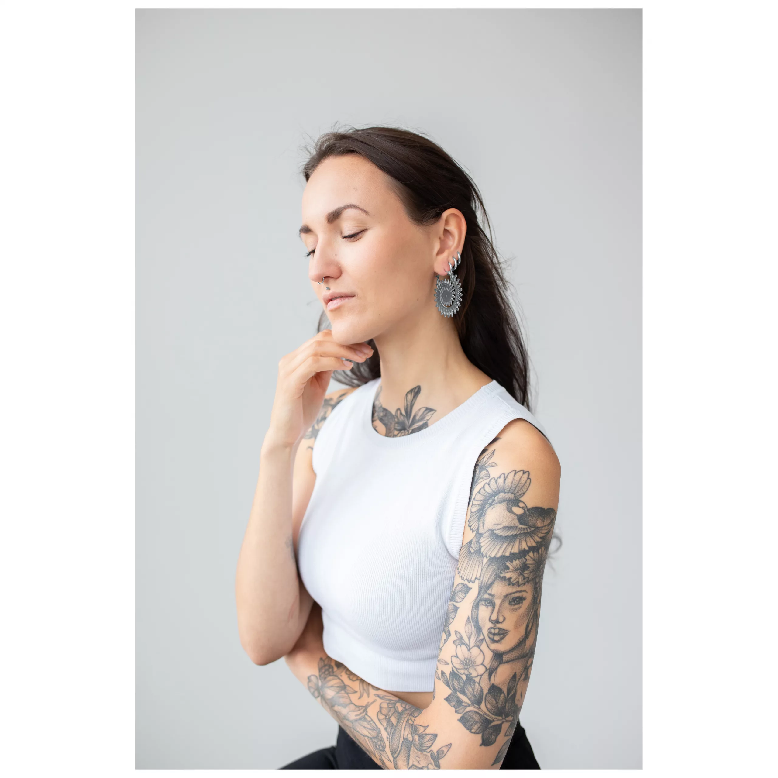 Floral Nautilus Hoops an Model Frau mit tätowiertem Arm trägt silberne Floral Nautilus Hoops vor grauem Hintergrund