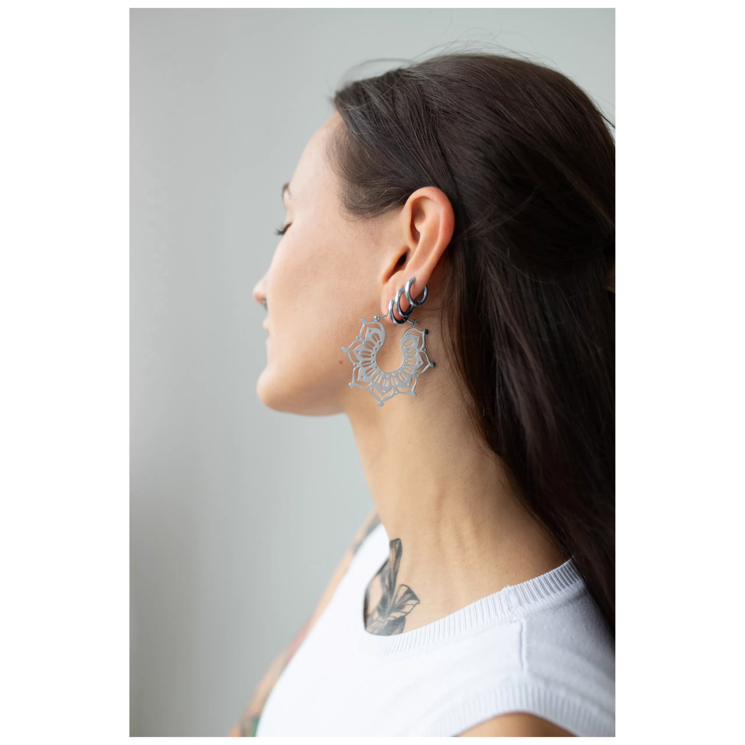 Silberne Magnolia Hoops Ohrringe im Ohr Frau mit langen Haaren trägt silberne Magnolia Hoops Ohrringe