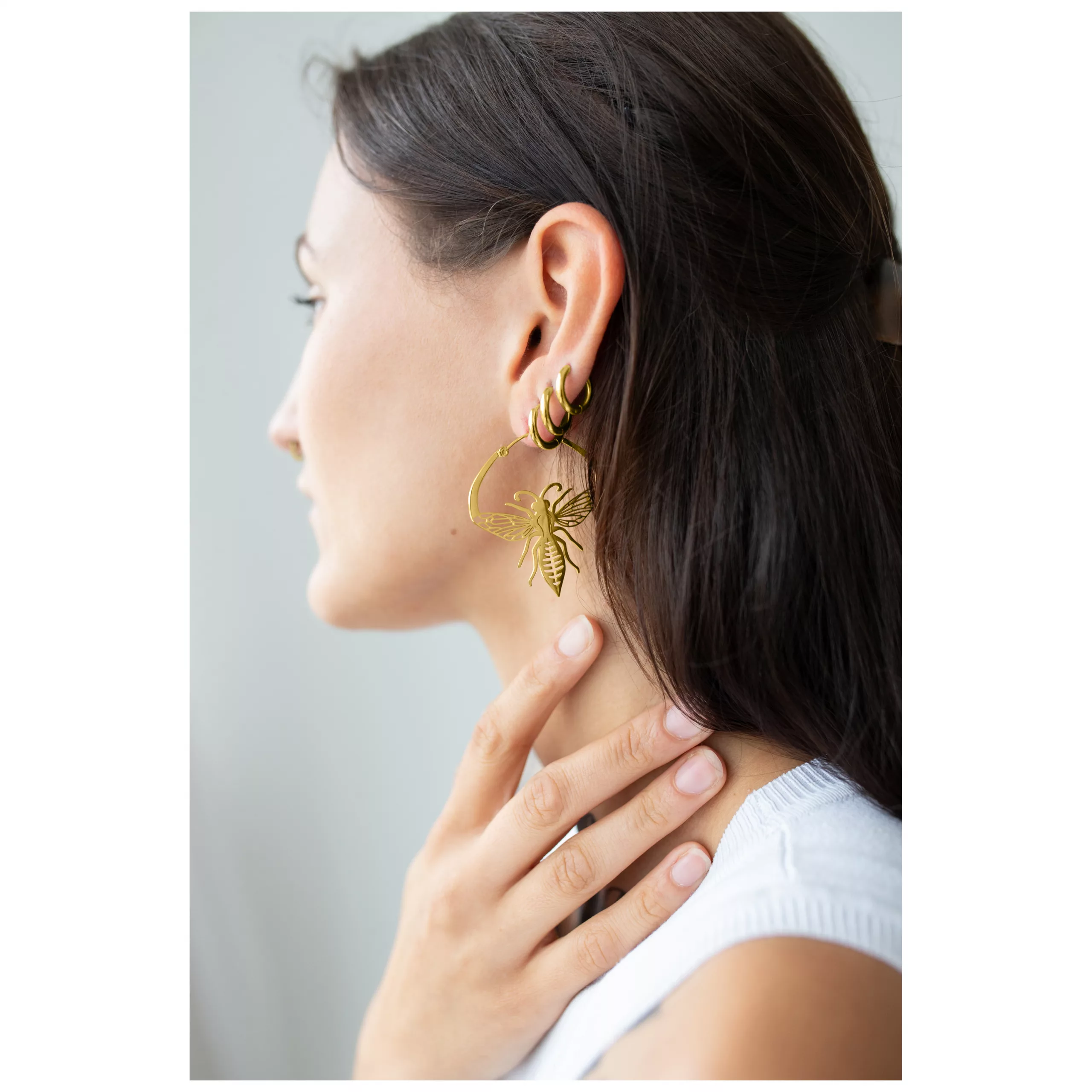 Goldene Bee Hoops Ohrschmuck Frau mit goldenen Bienen-Ohrringen aus Chirurgenstahl vor neutralem Hintergrund