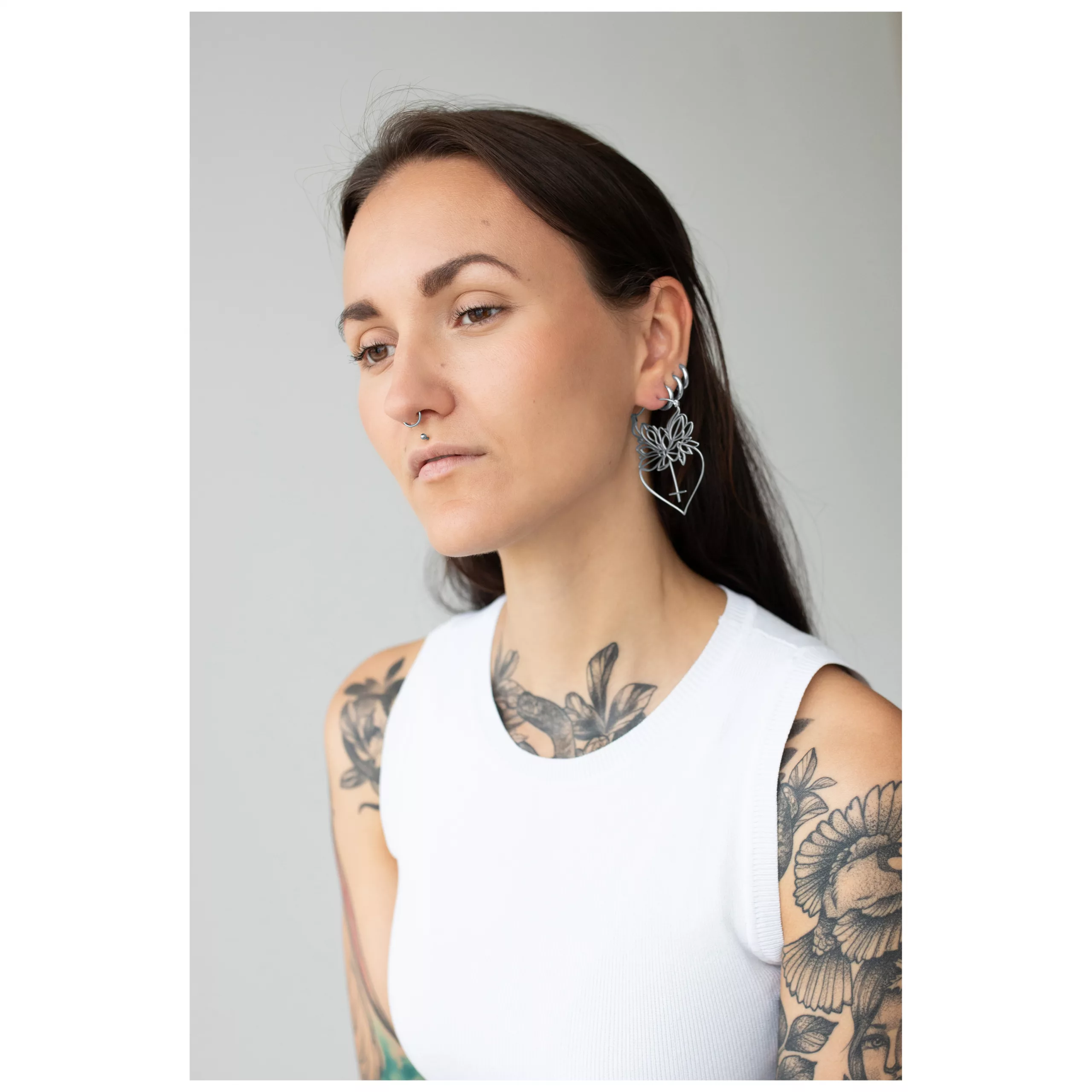 Silberne Dahlia Hoops Ohrringe am Ohr getragen Frau mit langen Haaren trägt silberne Dahlia Hoops Ohrringe vor grauem Hintergrund