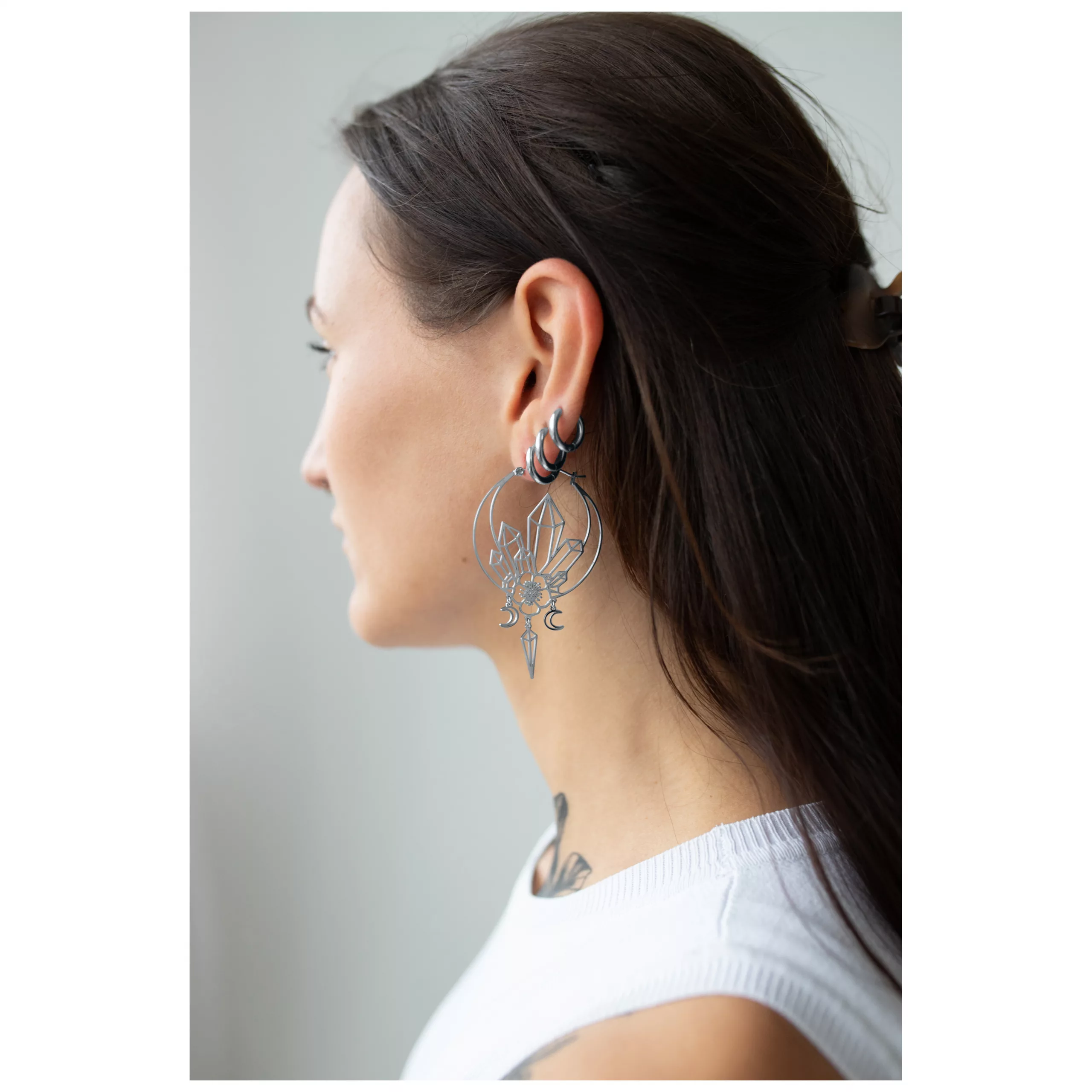Stylische Oracle Hoops Ohrringe in Schwarz Junge Frau mit langen Haaren trägt große, schwarze Oracle Hoops Ohrringe seitlich im Profil
