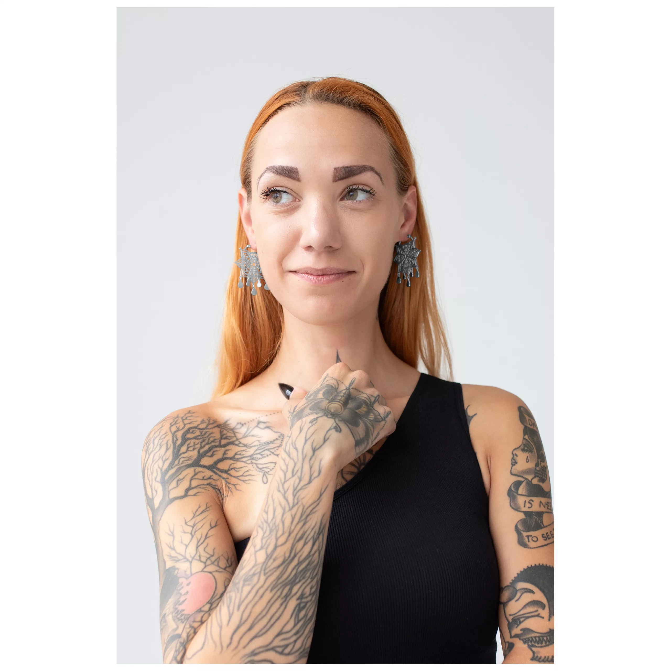 Silberne Mandala Hoops Ohrringe getragen Frau mit roten Haaren trägt silberne Mandala Ohrringe, Tattoos sichtbar