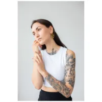 Frau mit weißen Top trägt goldene Pentagram Hoops, Tattoos sichtbar