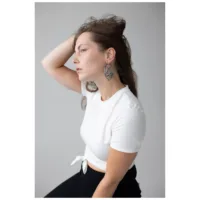 Lotus Hoops Ohrringe in Schwarz und Silber Frau mit Lotus Hoops Ohrringen aus Edelstahl in Schwarz und Silber auf grauem Hintergrund