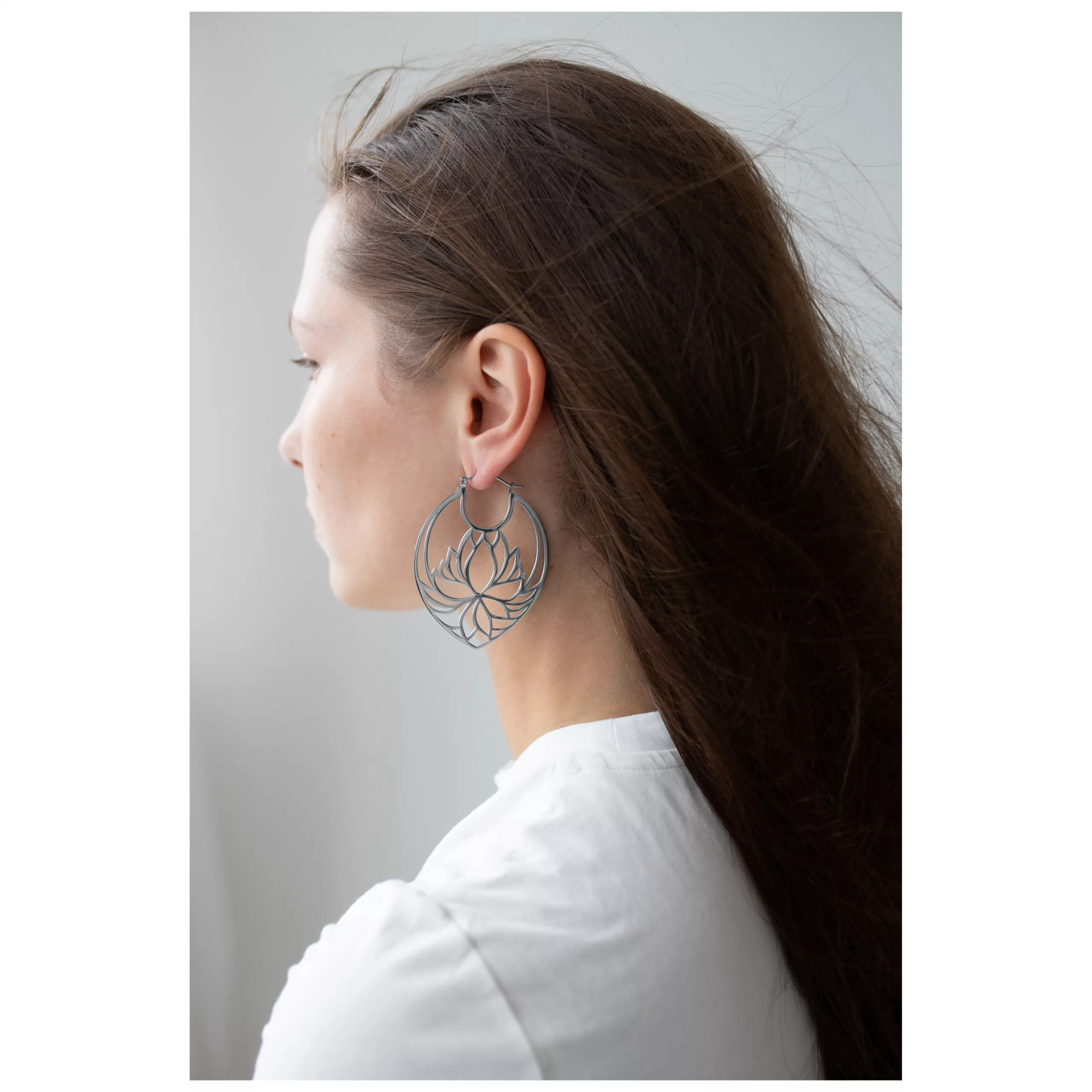 Lotus Hoops in elegantem Design Silberne Lotus Ohrringe an Frau mit langen Haaren und weißem Shirt