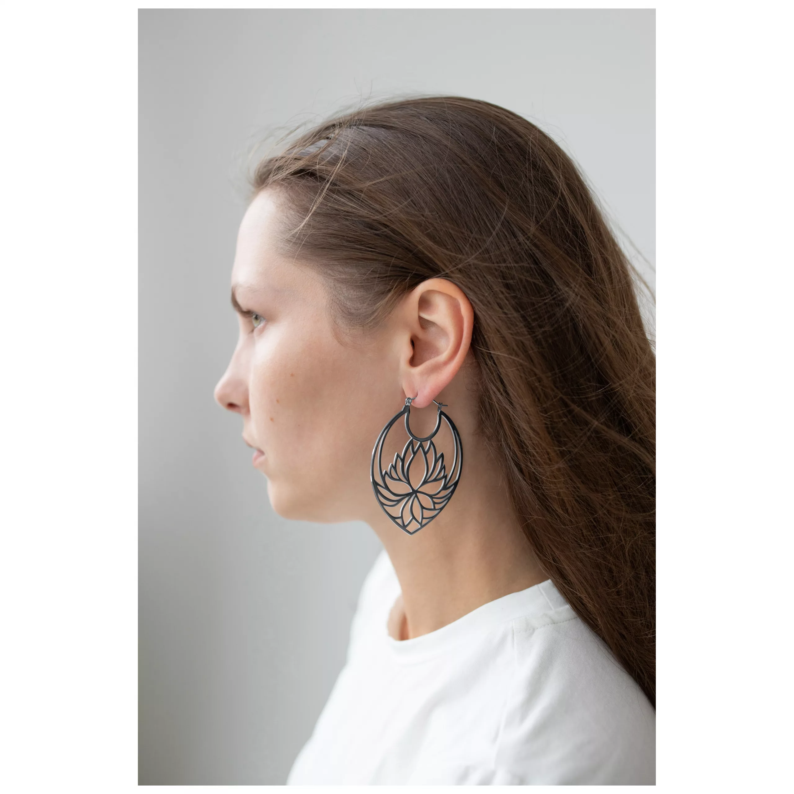 Lotus Hoops Ohrringe im auffälligen Design Frau mit langen Haaren trägt große schwarze Lotus Hoops Ohrringe