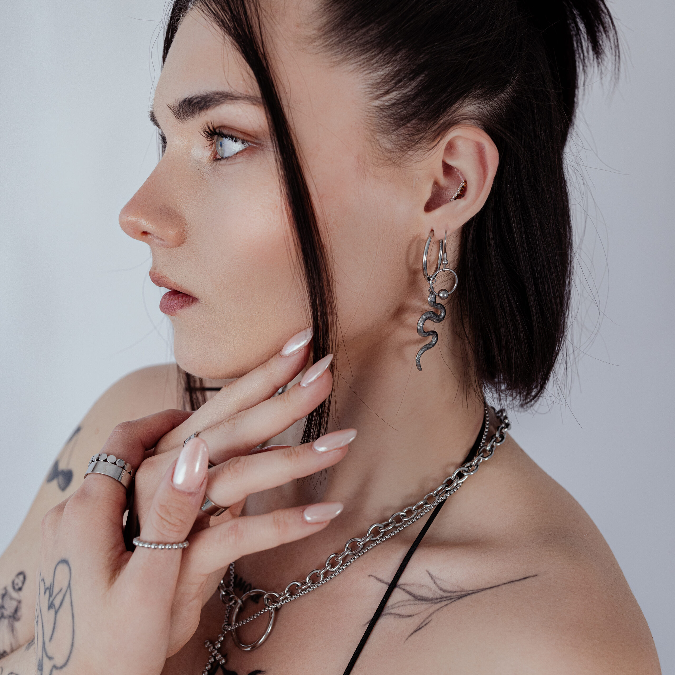 Stylische Big Snake Hoops Ohrringe in Silber Frau mit silbernen Big Snake Hoops Ohrringen, seitliches Profil