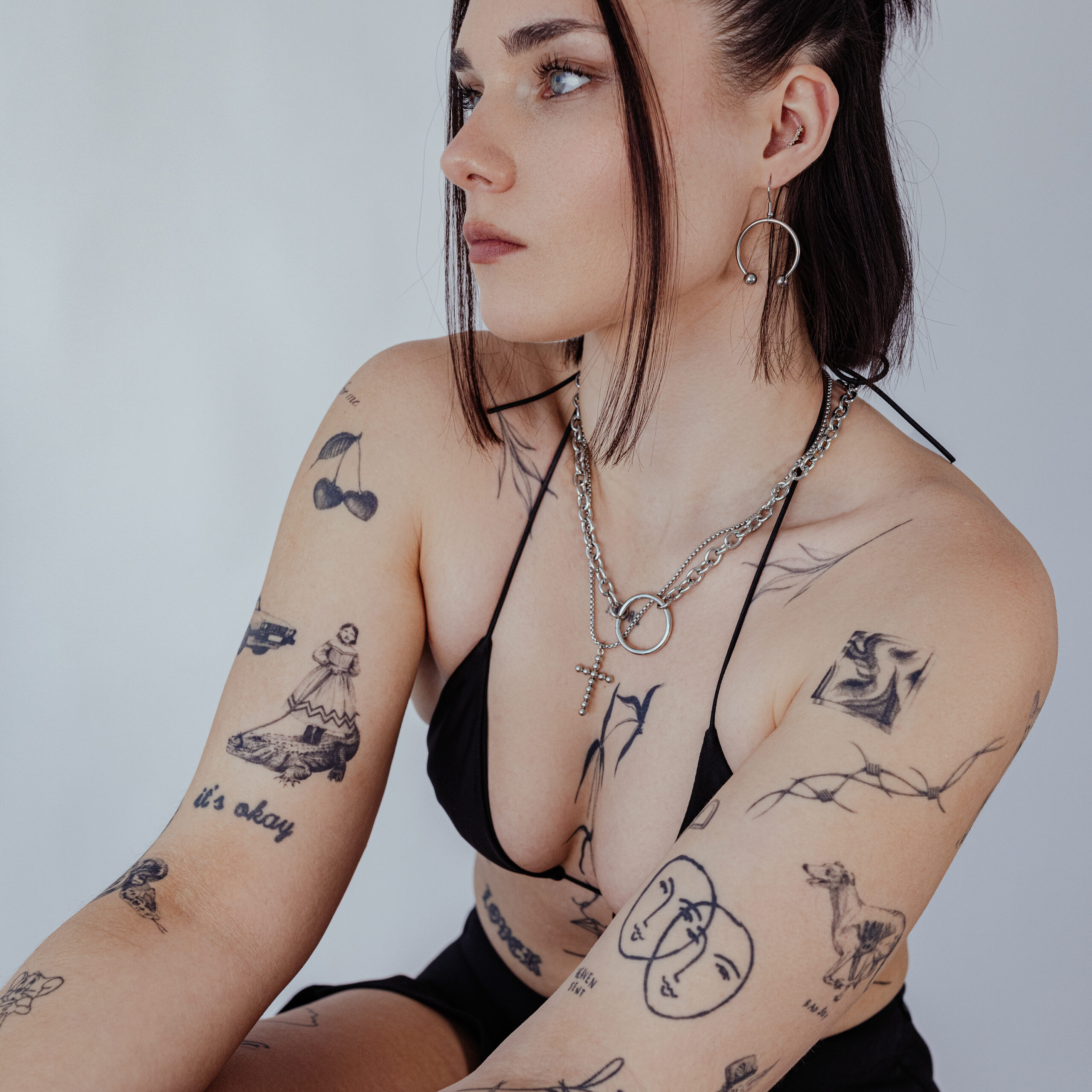 Silberne Circular Barbell Ohrringe im Set Frau mit silbernen Circular Barbell Ohrringen und Tattoos auf hellem Hintergrund