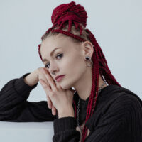 Silberne Little Ball Closure Hoops Ohrringe Frau mit roten Zöpfen trägt silberne Ohrringe vor hellem Hintergrund