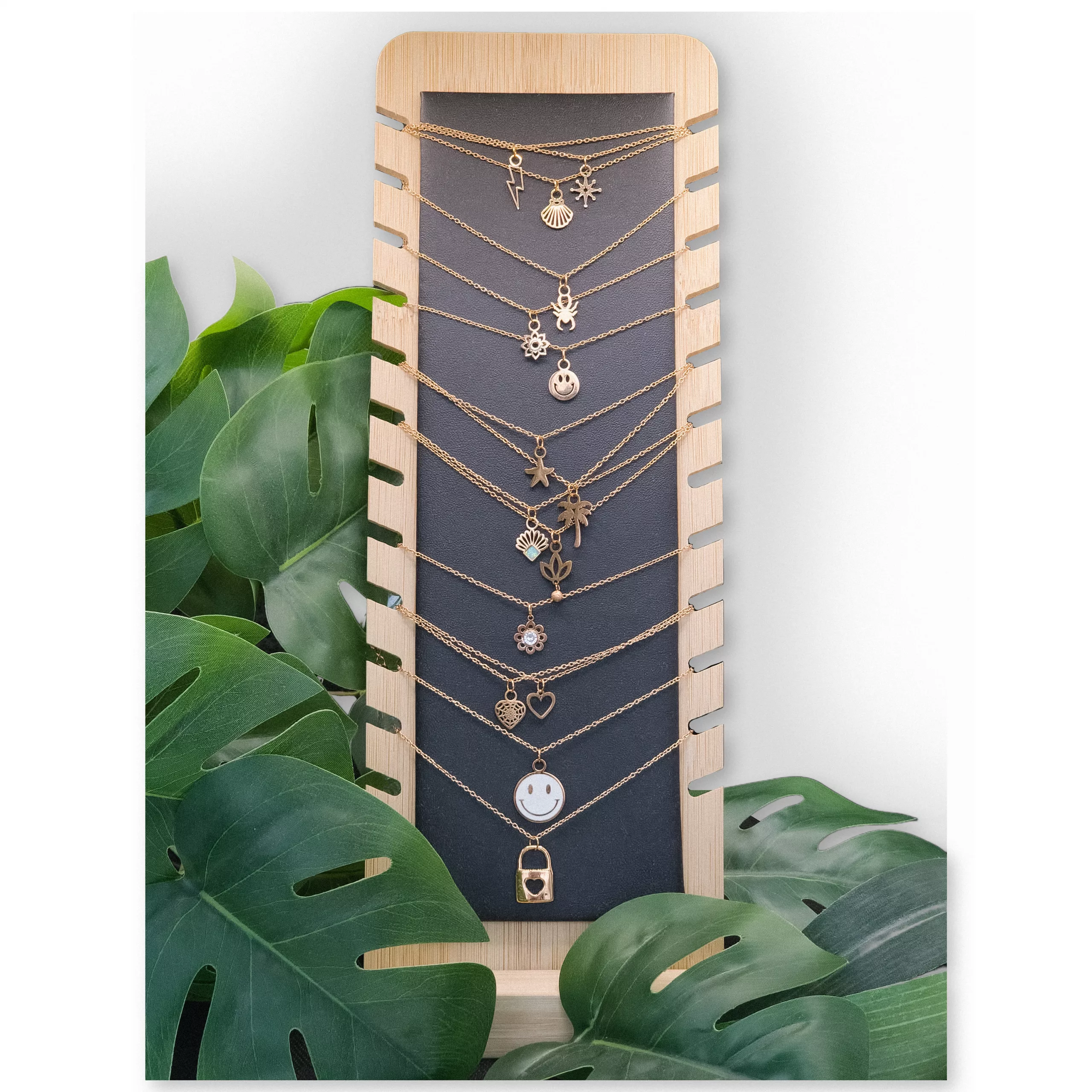 Schwarzes Schmuckdisplay aus Kunstleder und Holz Schwarzes Display aus Kunstleder und Holz mit Ketten und Pflanzen im Hintergrund