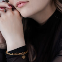 Elegantes Herz Armband in Gold für Damen Frau mit goldfarbenem Herz Armband auf schwarzem Hintergrund