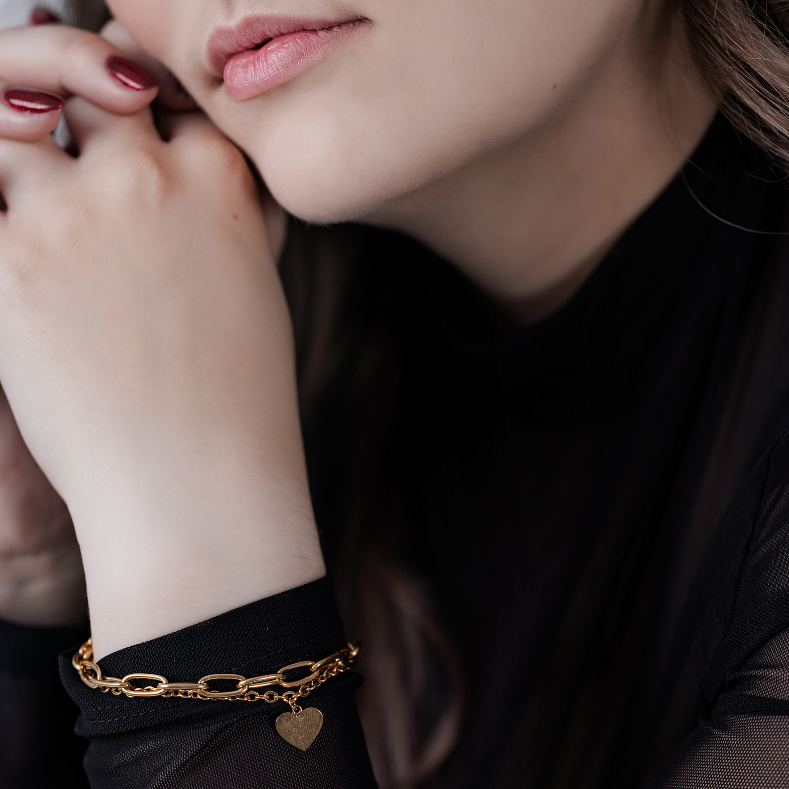 Elegantes Herz Armband in Gold für Damen Frau mit goldfarbenem Herz Armband auf schwarzem Hintergrund