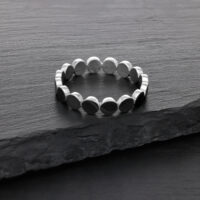 Silberner Plate-Ring aus Chirurgenstahl Silberner Ring aus Chirurgenstahl auf dunkler Steinoberfläche