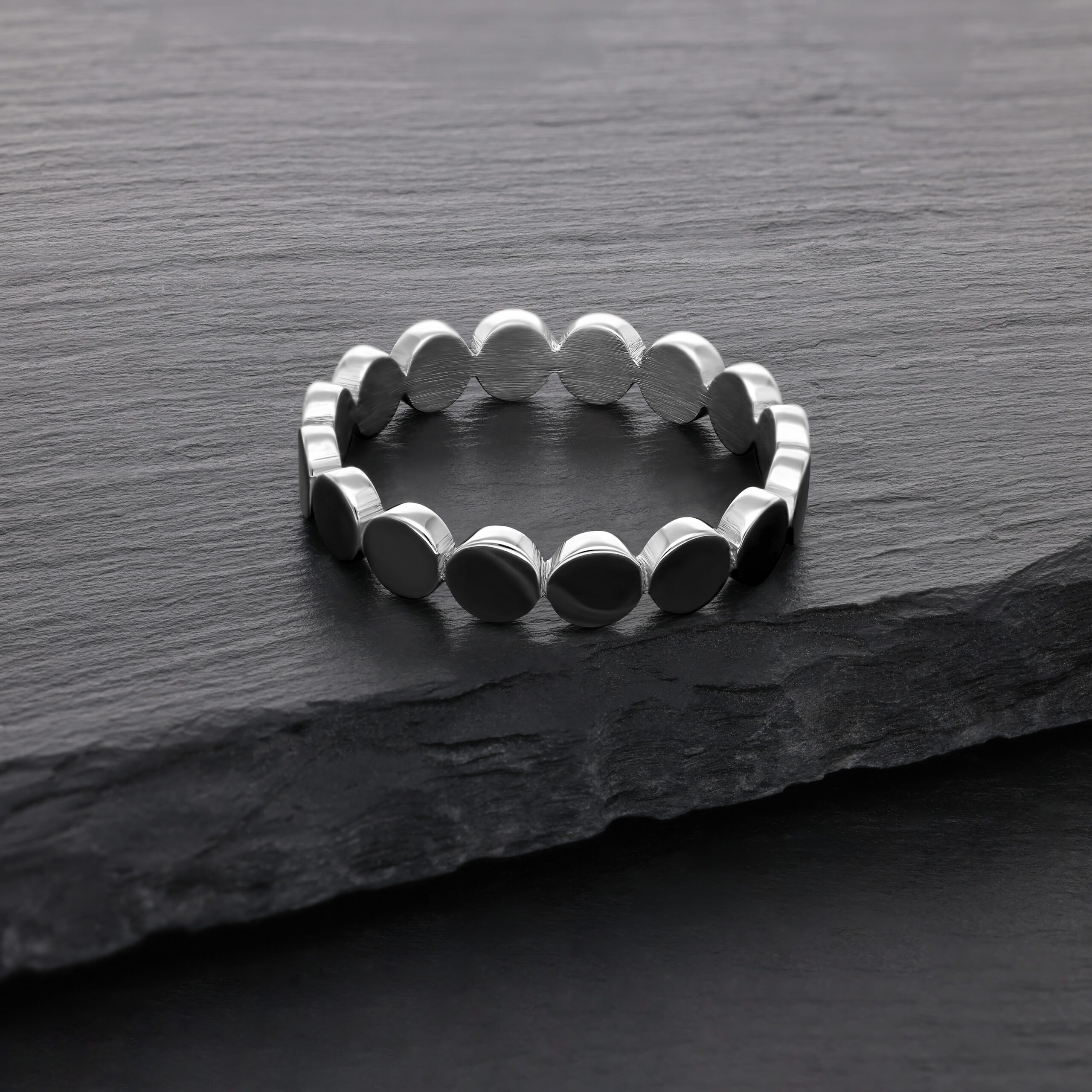 Silberner Plate-Ring aus Chirurgenstahl Silberner Ring aus Chirurgenstahl auf dunkler Steinoberfläche