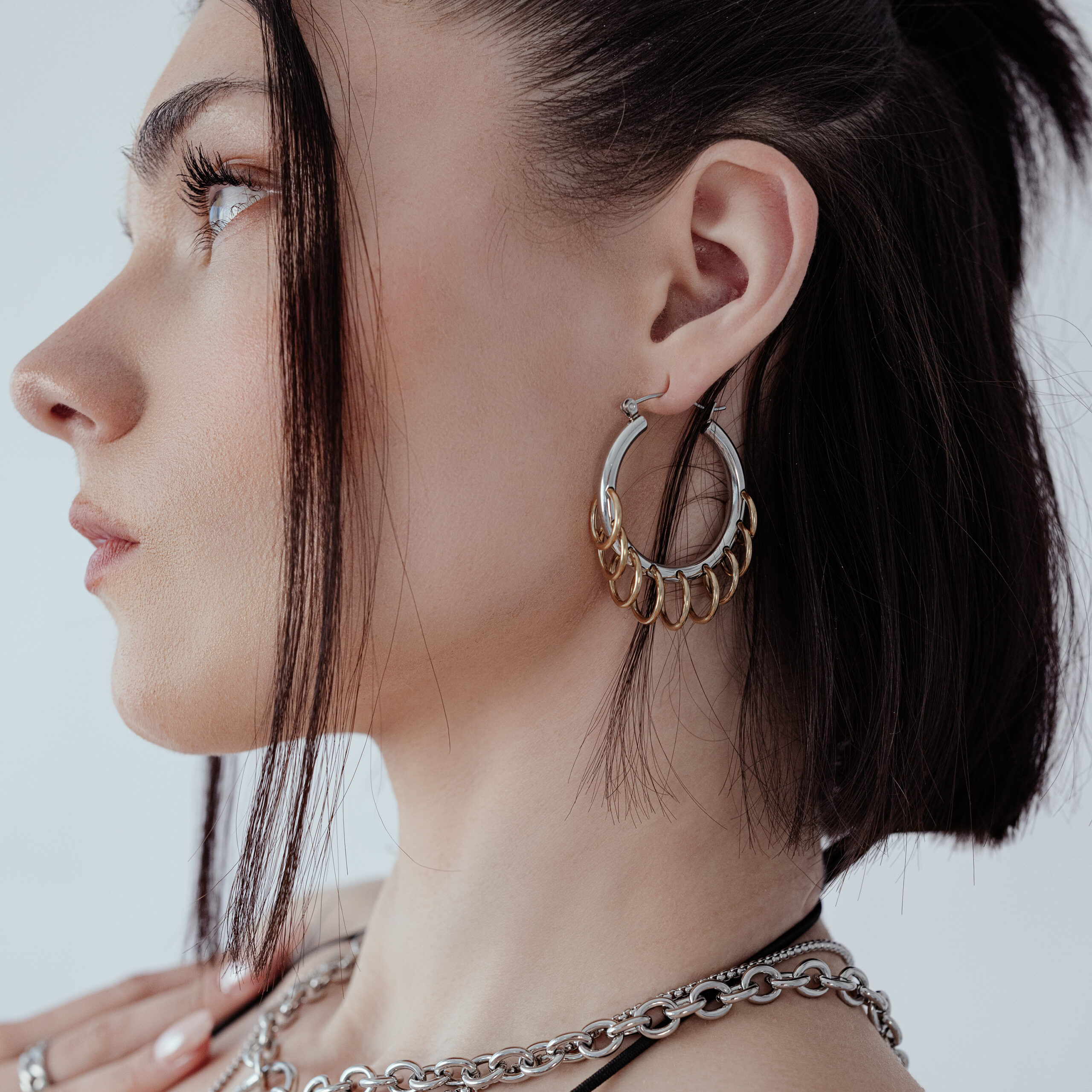 Stilvolle Hoops mit Loops in Silber und Gold Frau mit stilvollen, massiven Hoops mit Loops in Silber und Gold vor weißem Hintergrund