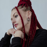 Wildcat Double Chain Ohrgewichte in Silber Frau mit roten Zöpfen trägt silberne Double Chain Ohrgewichte und schwarzen Pullover vor grauem Hintergrund