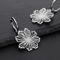 Zwei silberne Ohrringe mit Blumenmuster auf schwarzem Hintergrund