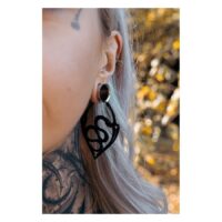 Schwarze Snake Hoops Ohrringe aus Stahl Nahaufnahme eines Ohres mit schwarzen Snake Hoops Ohrringen, Hintergrund unscharf